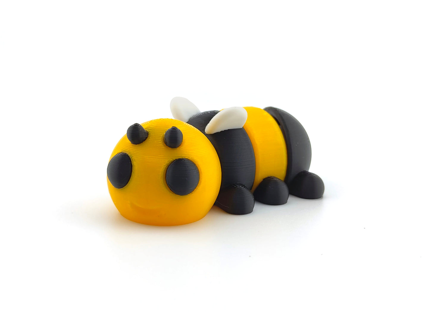 3D printed flat-lying bumblebee figure with yellow and black coloring and black details for eyes and antennae